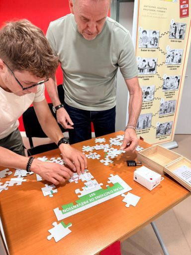 Deux personnes assemblent un puzzle sur une table en bois avec des pièces éparpillées.